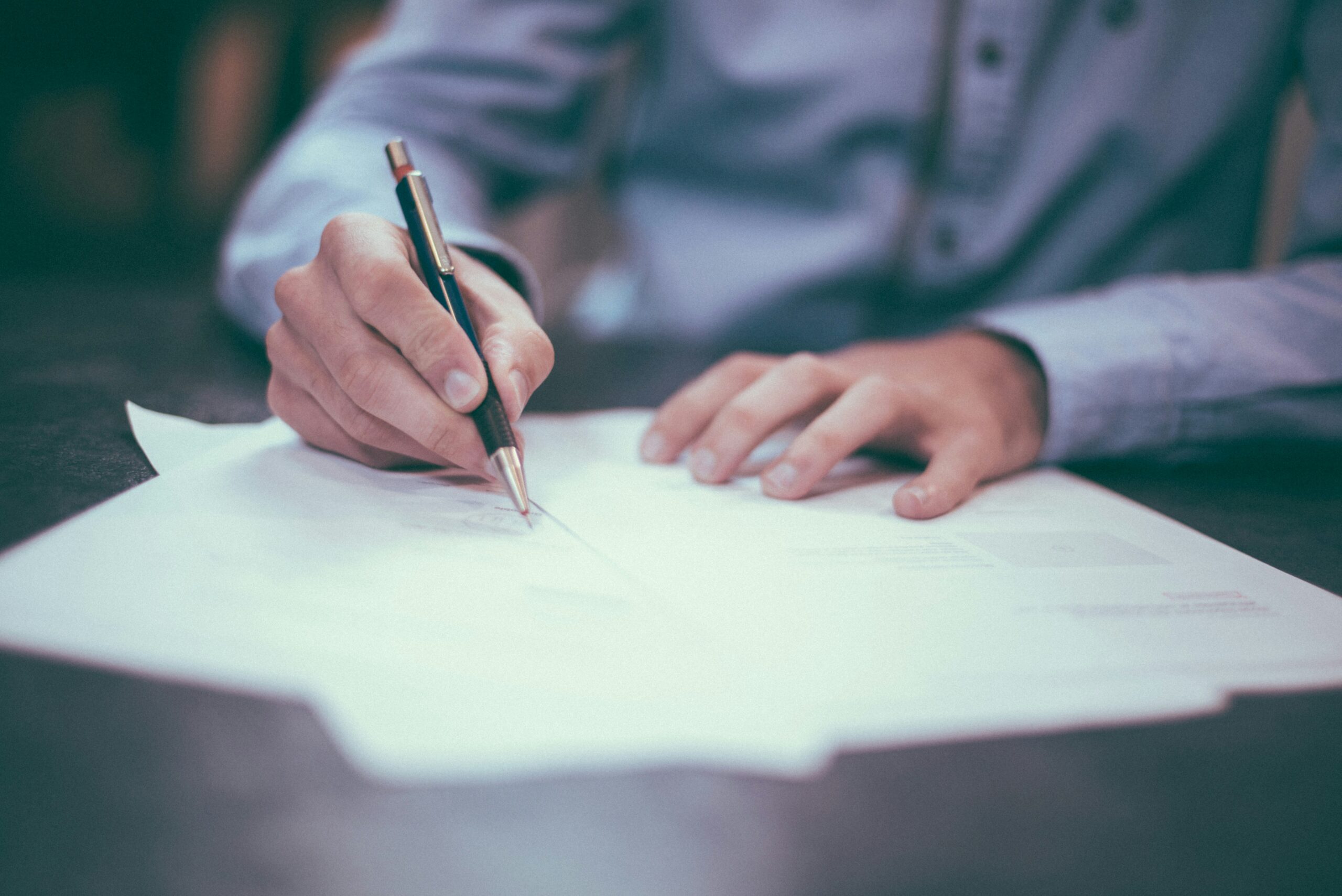 Close-up of lawyer signing corporate legal documents during contract preparation in Cambodia